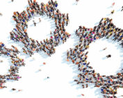 Photo of three cog-like shapes of different sizes, when you zoom in you see the cog is made of people