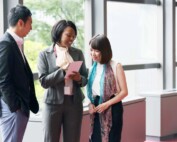 Picture of a woman looking over the shoulder of another woman holding a piece of paper and a man next to them