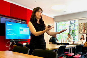 Woman wearing black shirt presenting in classroom setting to students attending workshop on Workplace Culture of Respect and Inclusion.