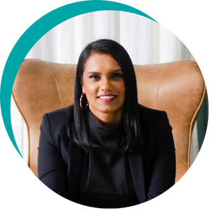 Women with dark hair and wearing a black jacket and shirt, smiling and sitting in a leather chair.